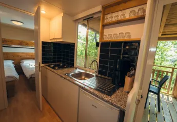 Angolo cucina compatto con lavandino, fornello e bicchieri, vicino a camera e terrazza al Cottage Classic, Chianti Glamping Resort.
