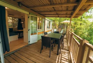 Terrasse couverte en bois du Cottage Classic avec table à manger, vue sur la forêt, Chianti Glamping Resort, Italie.