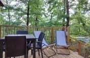Holzterrasse mit Gartenmöbeln und Blick auf grüne Bäume, Cottage Clever im Chianti Glamping Resort, Italien.