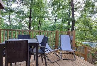 Houten terras met tuinmeubilair en uitzicht op bomen bij Cottage Clever, Chianti Glamping Resort, Italië.