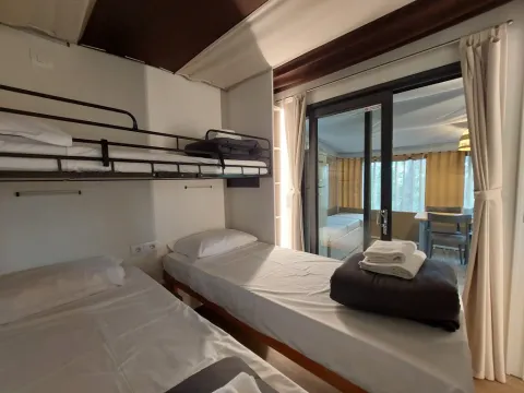 Kamer met stapelbed en eenpersoonsbedden in Cottage Clever bij Chianti Glamping Resort, Italië, met uitzicht op terras.