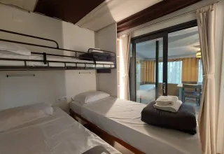 Kamer met stapelbed en eenpersoonsbedden in Cottage Clever bij Chianti Glamping Resort, Italië, met uitzicht op terras.