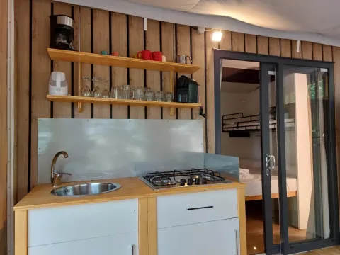 Keukenhoek in Cottage Clever bij Chianti Glamping Resort in Italië, met gootsteen, fornuis en planken.