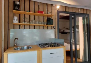Keukenhoek in Cottage Clever bij Chianti Glamping Resort in Italië, met gootsteen, fornuis en planken.