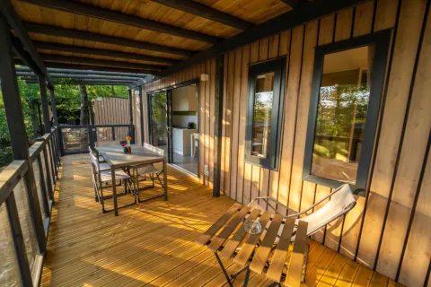 Hölzerne Veranda einer Lodge mit Esstisch, Stühlen und Blick auf Natur, ideal zum Entspannen.