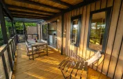 Hölzerne Veranda einer Lodge mit Esstisch, Stühlen und Blick auf Natur, ideal zum Entspannen.