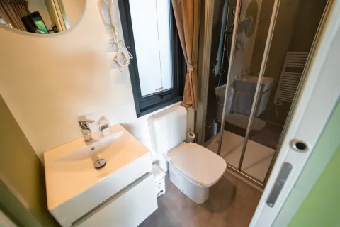 Salle de bain moderne au Cottage Next L Evo du Chianti Glamping Resort avec douche, WC et lavabo.