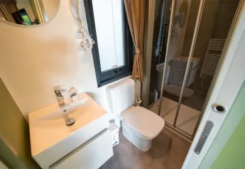 Baño moderno en Cottage Next L Evo, Chianti Glamping Resort, con ducha, inodoro y lavabo elegante.