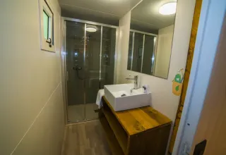 Salle de bain moderne avec douche et lavabo en bois au Cottage Spotty du Chianti Glamping Resort en Italie.