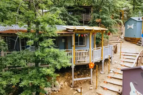 Photo du lodge Cottage Spotty en forêt, entouré d'arbres, de sentiers en bois et de charmantes terrasses.