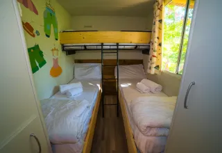 Dormitorio infantil con tres camas individuales, arte colorido en la pared y ventana en Cottage Spotty, Chianti Glamping Resort.