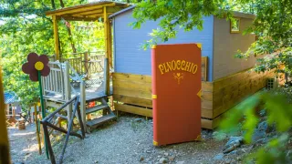 Ein farbenfroher Bereich der Cottage Spotty Special Lodge mit großem Pinocchio-Buch und Bäumen.