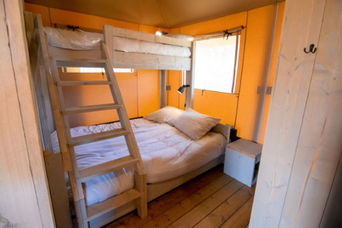 Houten lodge slaapkamer met stapelbed en tweepersoonsbed bij De Lodge, Glamping de Bosweide, Nederland.