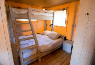 Houten lodge slaapkamer met stapelbed en tweepersoonsbed bij De Lodge, Glamping de Bosweide, Nederland.