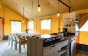 Binnenaanzicht van De Lodge bij Glamping de Bosweide in Nederland, met eettafel en keuken te zien.
