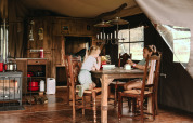 Due bambini si divertono in una cabina glamping rustica, seduti a un tavolo di legno dall'atmosfera accogliente.