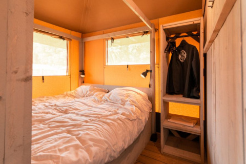 Binnenaanzicht van safaritent 'De Medley' bij Glamping de Bosweide in Nederland met bed en kledingkast.