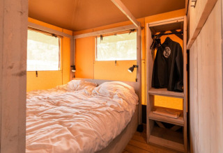 Binnenaanzicht van safaritent 'De Medley' bij Glamping de Bosweide in Nederland met bed en kledingkast.