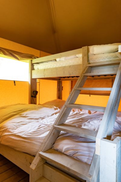 Staplebed in safaritent De Medley bij Glamping de Bosweide, Nederland, met houten trap en sfeervol licht.