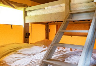 Staplebed in safaritent De Medley bij Glamping de Bosweide, Nederland, met houten trap en sfeervol licht.