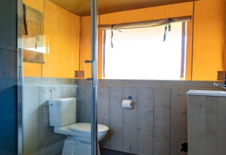 Badkamer in safaritent 'De Medley' met douche, toilet en raam bij Glamping de Bosweide in Nederland.