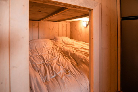 Gezellige slaapruimte met houten wanden en sfeerverlichting in een safaritent bij Glamping de Bosweide.