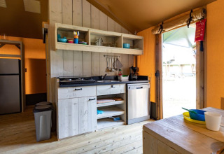 Keuken in safaritent De Medley bij Glamping de Bosweide in Nederland, met houten interieur en eethoek.