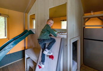 Jongen klimt op een klimwand in de safari tent De Medley bij Glamping de Bosweide in Nederland.