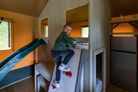 Jongen klimt op een klimwand in de safari tent De Medley bij Glamping de Bosweide in Nederland.