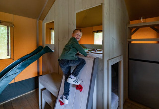 Jongen klimt op een klimwand in de safari tent De Medley bij Glamping de Bosweide in Nederland.