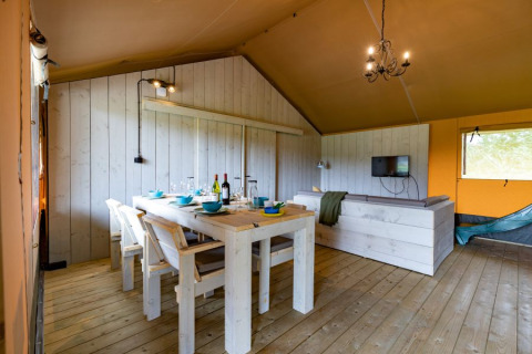 Ruim ingerichte safaritent met eetgedeelte en zithoek bij Glamping de Bosweide in Nederland.