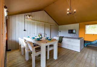 Ruim ingerichte safaritent met eetgedeelte en zithoek bij Glamping de Bosweide in Nederland.