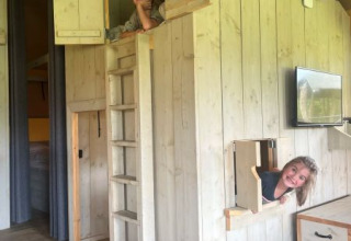 Zwei Kinder spielen in einem hölzernen Spielhaus in einem Safarizelt bei Glamping de Bosweide, Niederlande.