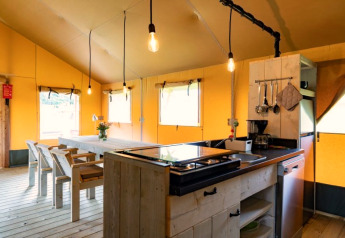 Interieur van een safaritent bij Glamping de Bosweide in Nederland, met houten meubilair en keuken.