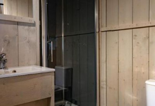 Badeværelse med bruser, håndvask og toilet i Safari-teltet på Glamping de Bosweide, Holland.