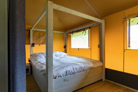 Vista interna di una tenda safari con letto confortevole al Glamping de Bosweide nei Paesi Bassi.