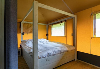 Vista interna di una tenda safari con letto confortevole al Glamping de Bosweide nei Paesi Bassi.