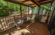 Überdachte Holzterrasse mit Gartenmöbeln und Blick auf Lodges, Cube Suite im Chianti Glamping Resort, Italien.