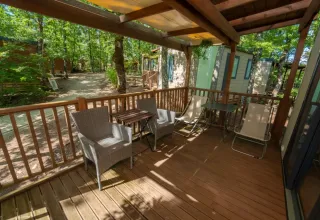 Overdekt houten terras met tuinmeubilair bij Cube Suite in Chianti Glamping Resort, Italië, omgeven door bomen.