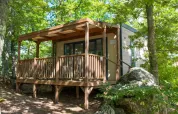 Eine Cube Suite-Lodge mit Holzveranda im Chianti Glamping Resort, Italien, umgeben von grüner Natur.