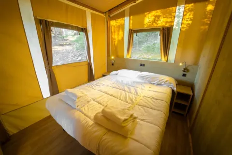 Gemütliches Lodge Tent Deluxe mit Doppelbett am Chianti Glamping Resort in Italien und Blick in die Natur.
