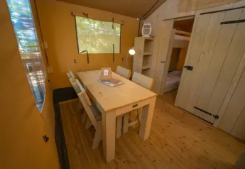 Vista interna di una zona pranzo accogliente in tenda safari al Chianti Glamping Resort in Italia.
