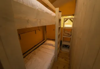 Interieur met stapelbedden en planken in een Safari Tenten bij Chianti Glamping Resort in Italië.
