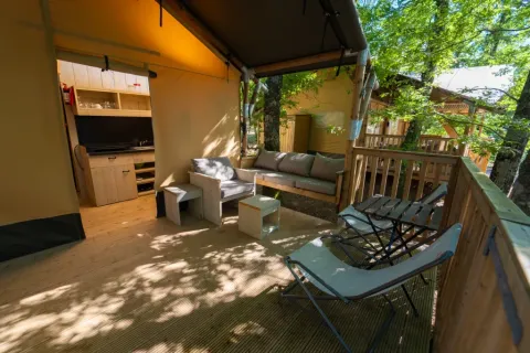Safari Tenten veranda en zithoek bij Chianti Glamping Resort in Italië, met comfortabele zitjes tussen bomen.