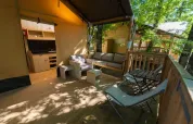 Gemütliche Safari-Tententerrasse im Chianti Glamping Resort, Italien, mit Sitzmöglichkeiten im Grünen.