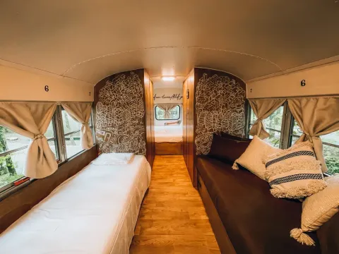 Intérieur du tiny house 'Schoolbus' avec lits confortables au Chianti Glamping Resort en Italie.