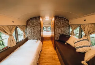 Intérieur du tiny house 'Schoolbus' avec lits confortables au Chianti Glamping Resort en Italie.