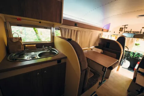 Intérieur d'une tiny house bus scolaire au Chianti Glamping Resort en Italie avec cuisine et coin repas.