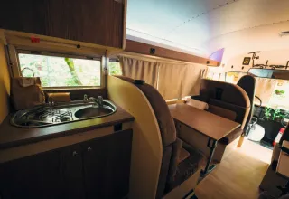 Intérieur d'une tiny house bus scolaire au Chianti Glamping Resort en Italie avec cuisine et coin repas.