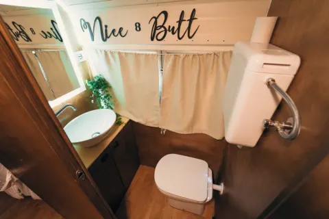 Petite salle de bain dans la tiny house 'Schoolbus' au Chianti Glamping Resort, Italie, avec texte humoristique.